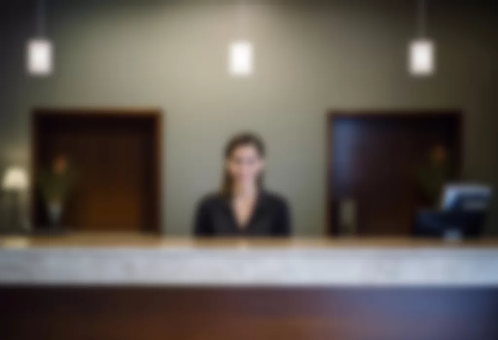 An event concierge standing at a service desk, symbolising the professional and personalised support offered through Smart Event Management’s Event Concierge Services, ensuring a seamless and enjoyable experience for all event attendees.