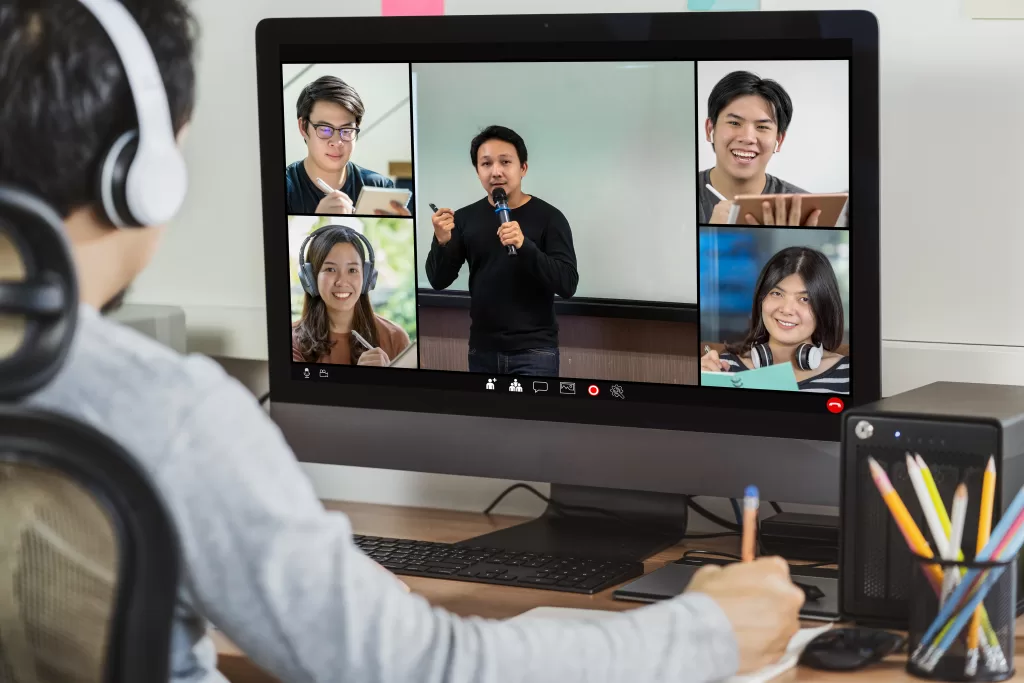 A person participating in a virtual meeting or webinar, with multiple attendees visible on a computer screen. The scene captures the essence of remote engagement and learning, highlighting the importance of live streaming services in connecting people and facilitating communication across distances.